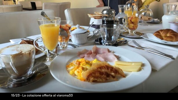 Un desayuno con huevos revueltos, jamón y queso, un vaso de jugo de naranja y una cafetera sobre una mesa.