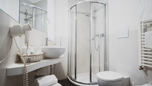 Un baño moderno con cabina de ducha de vidrio, un lavamanos blanco y un inodoro.