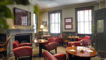A restaurant with red leather chairs, wooden tables, and a fireplace.