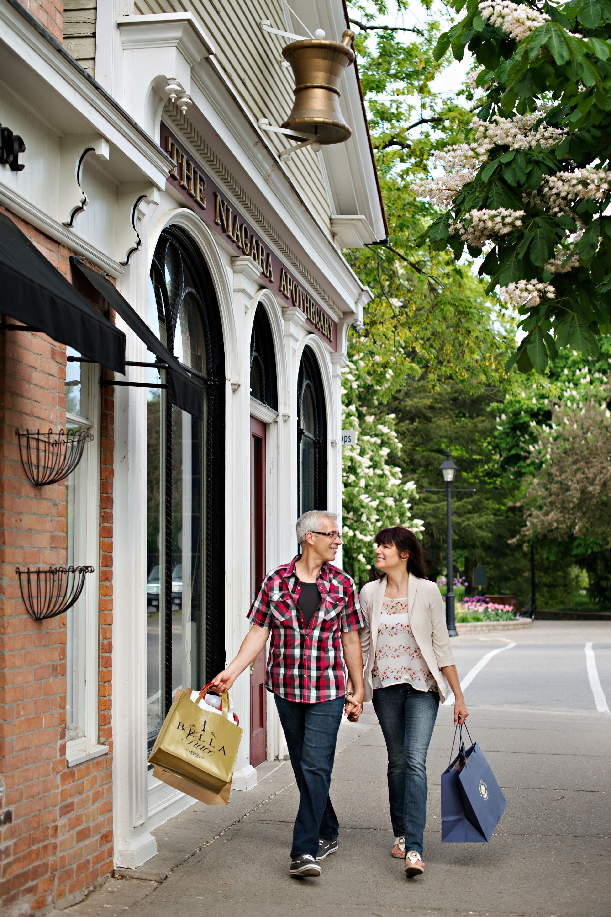 A couple walking past a building with arched windows and a sign that reads "The Niagara Apartments."