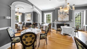 A dining room with a fireplace, white walls, and wooden flooring.