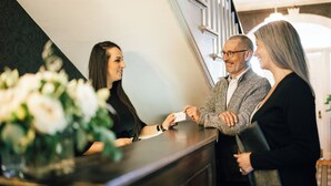 A reception desk with a vase of flowers, a staircase, and a modern interior design.