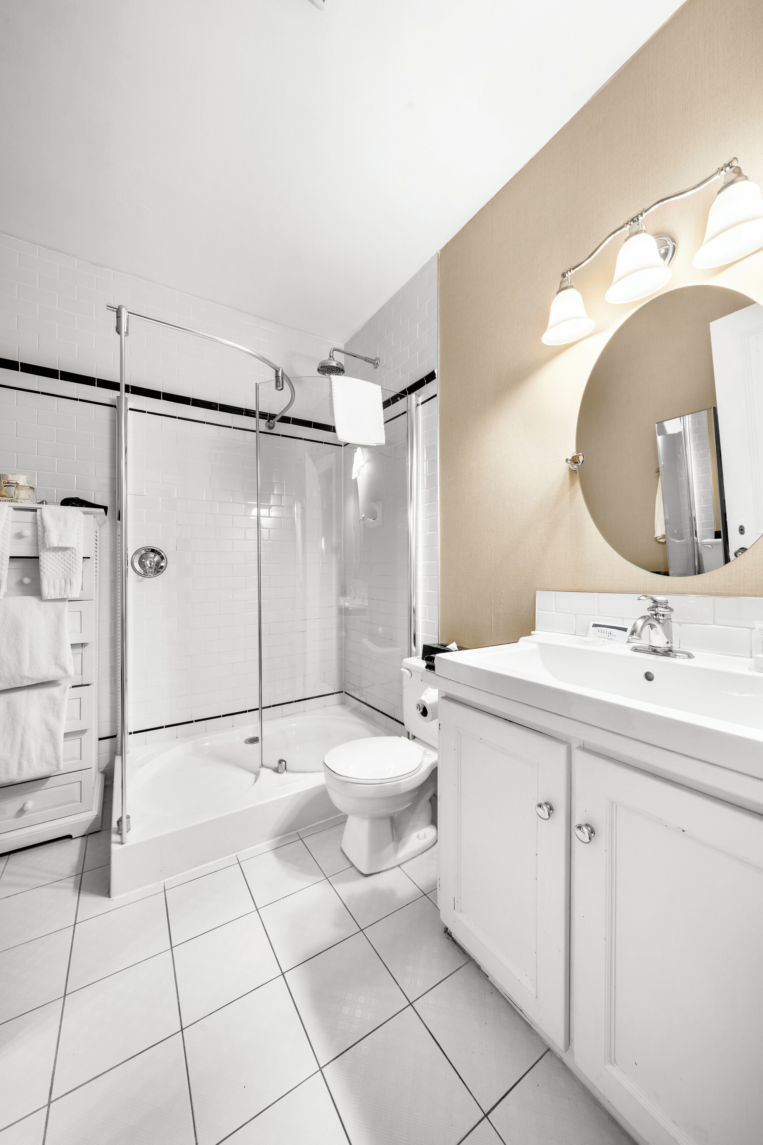 A modern bathroom with a glass-enclosed shower, a white sink, and a large mirror.
