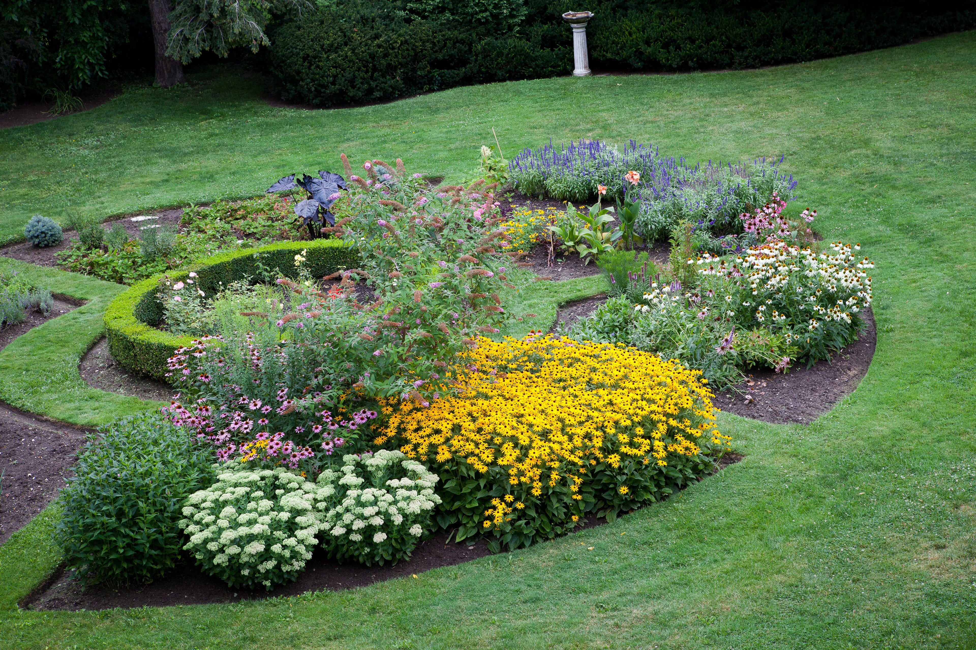 A well-maintained garden with various flower beds and a central circular lawn area.