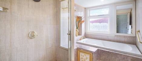 Un baño con ducha, bañera y ventana.