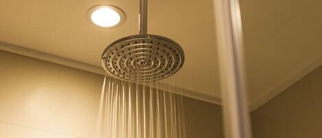 A showerhead with a circular glass cover and a visible "T" and "N" logo.