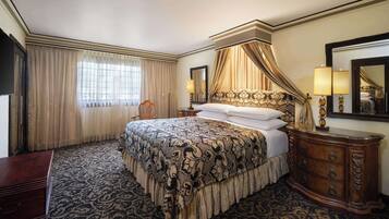 A hotel room with a large bed, a wooden dresser, a mirror, and a window with curtains.