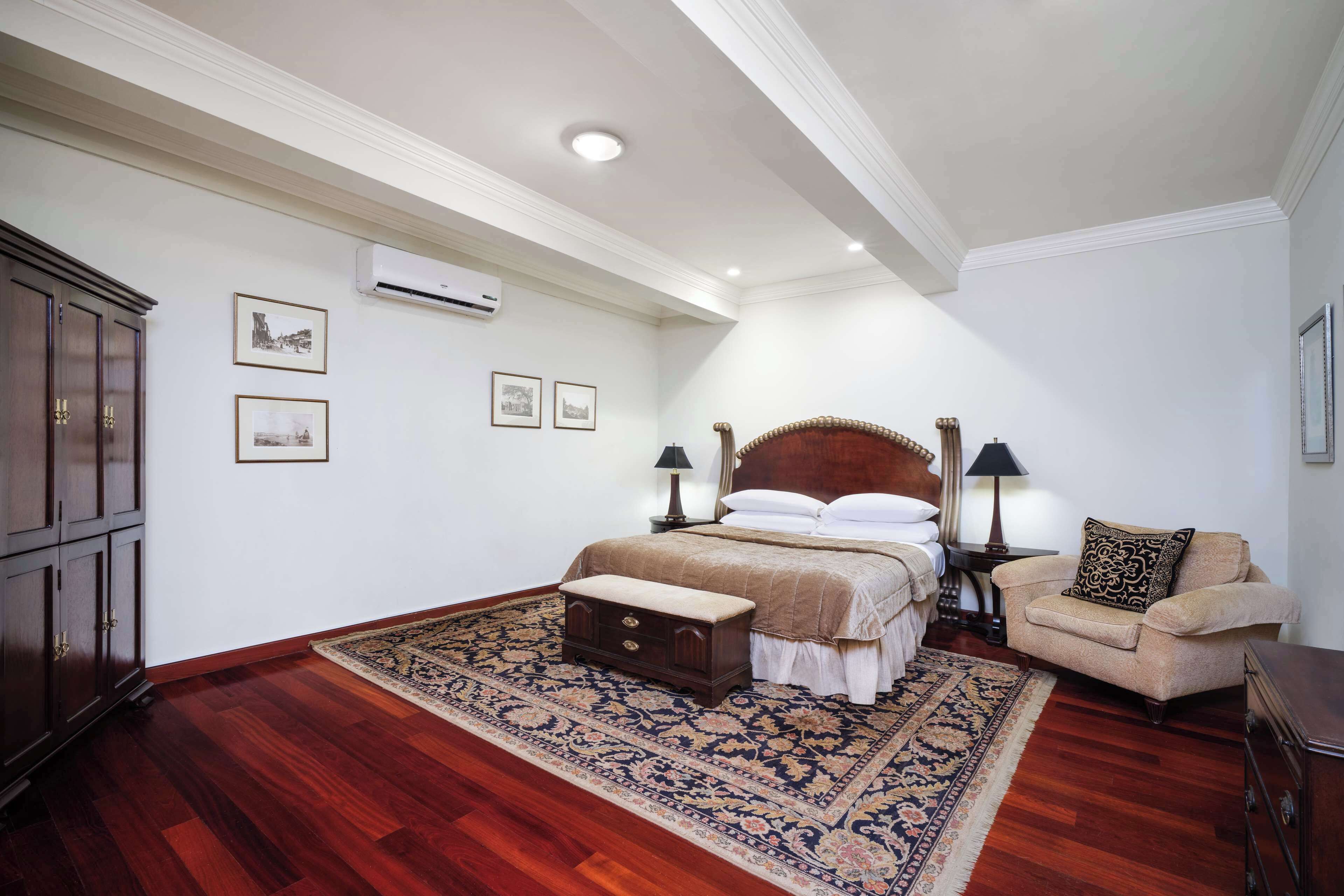 A bedroom with a large bed, a nightstand, a chair, a dresser, and a patterned rug.