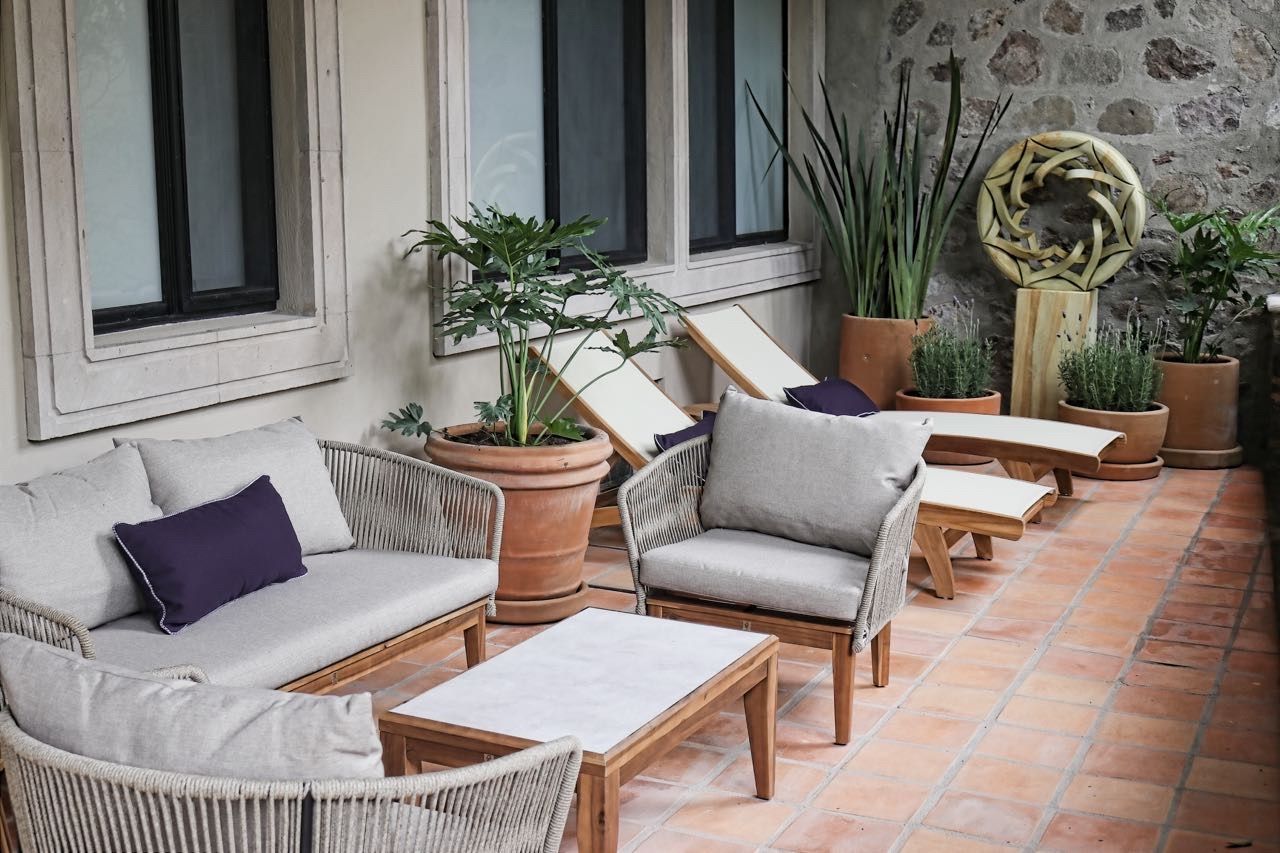 Un área de estar al aire libre con muebles de mimbre y plantas en macetas.