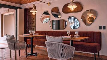 Interior de restaurante con techo de ladrillo, espejos redondos y una mesa de madera lista para comer.