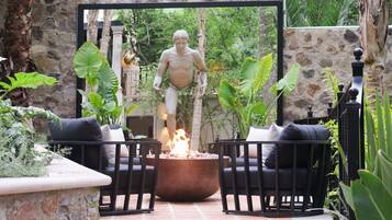 Un patio con una fogata, asientos exteriores y una estatua.