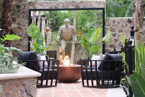 Un patio con una fogata, asientos exteriores y una estatua.