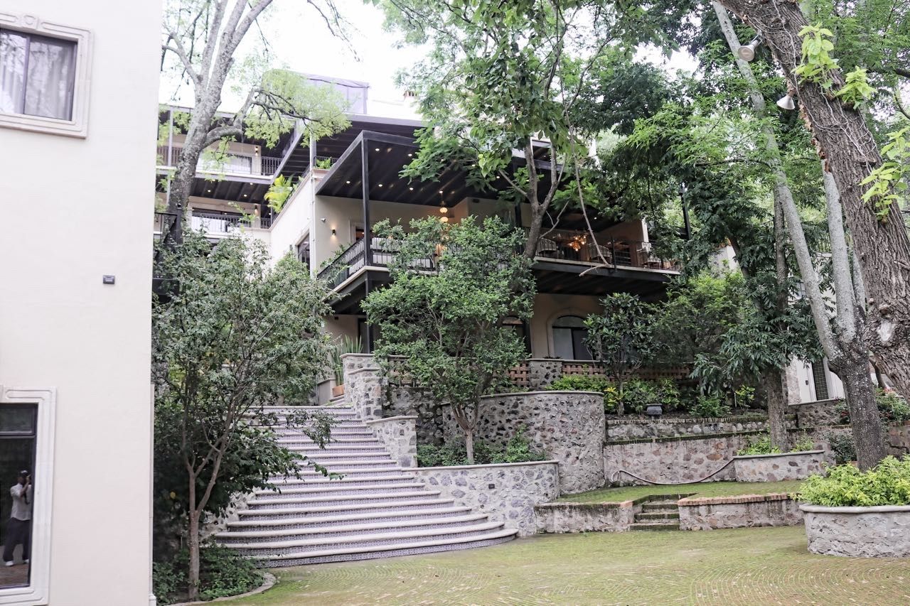 Un edificio de varios niveles con escaleras exteriores, rodeado de vegetación y árboles.