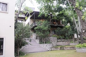 Um edifício com vários níveis e escadas externas, cercado por vegetação e árvores.