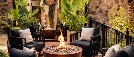 An outdoor patio with stone walls, a fire pit, and black outdoor furniture.