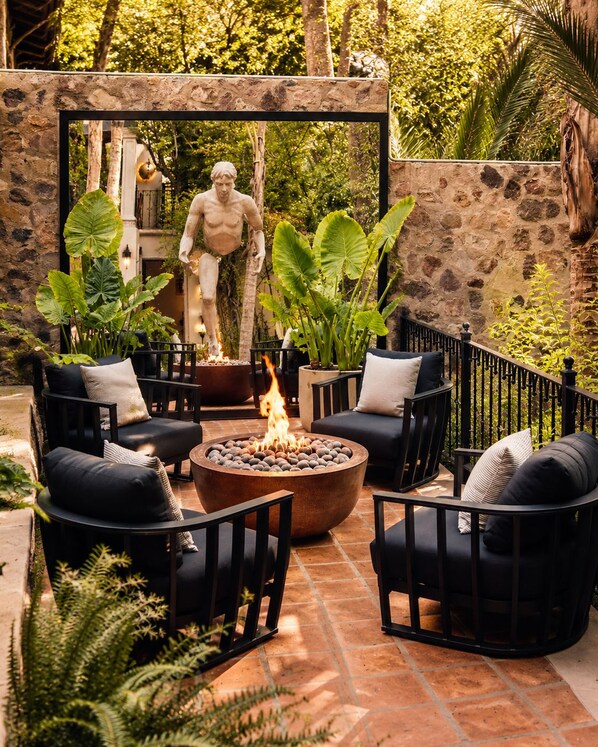 An outdoor patio with stone walls, a fire pit, and black outdoor furniture.