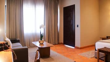Habitación de hotel con cama, sofá, una mesita de café y una planta en maceta.