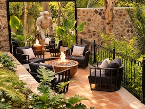 An outdoor patio area with stone walls, a fire pit, and seating arrangements. - La Puertecita Boutique Hotel (San Miguel de Allende)