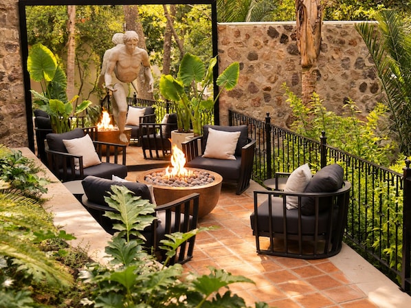 An outdoor patio area with stone walls, a fire pit, and seating arrangements.