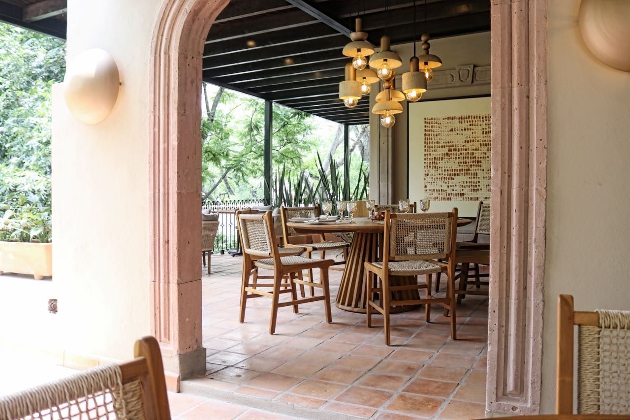 Un área de comedor al aire libre con muebles de madera y suelo de baldosas.