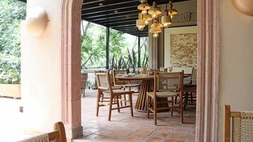 Un área de comedor al aire libre con muebles de madera y suelo de baldosas.