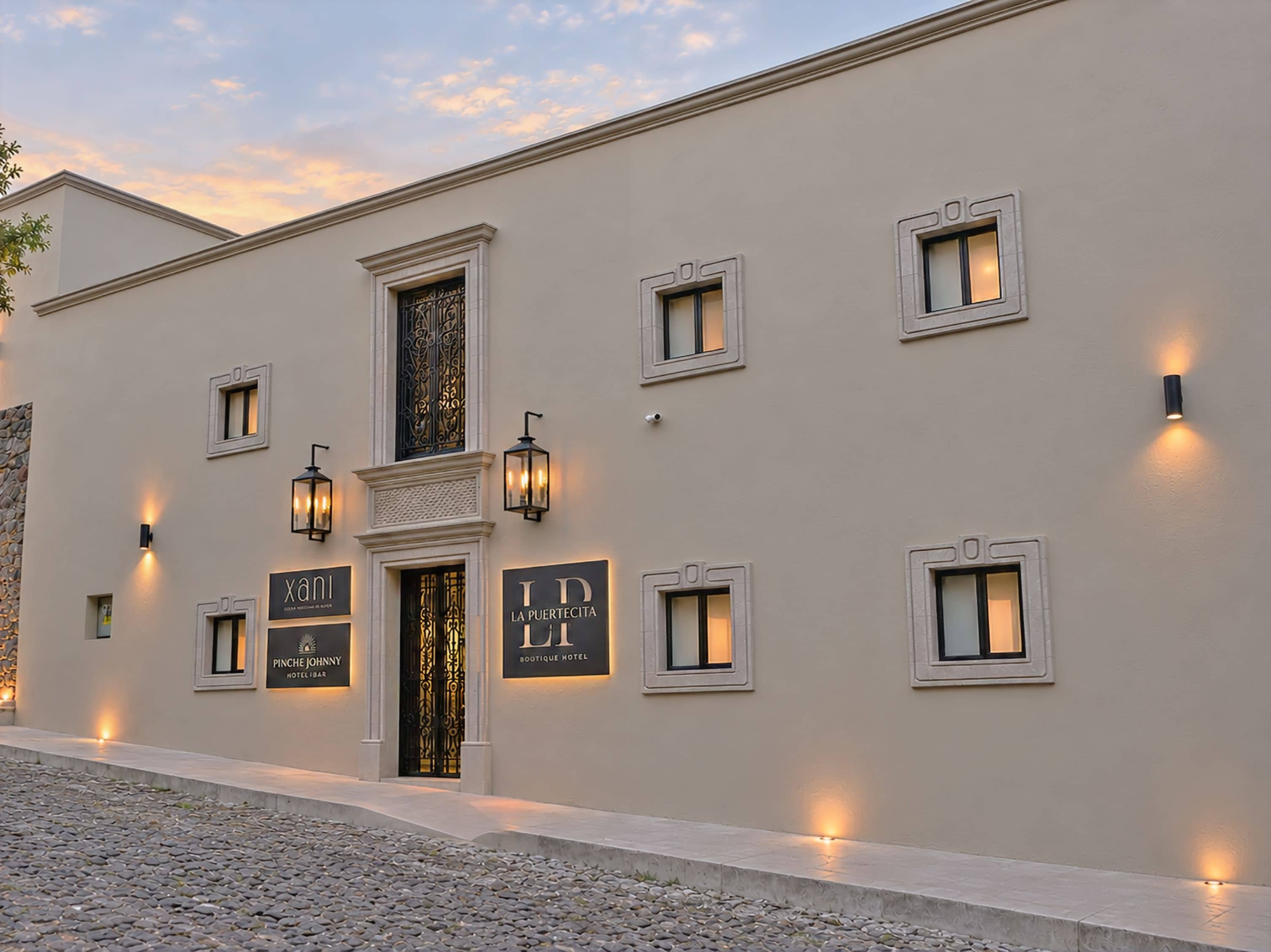 Un edificio con varias ventanas y puertas, algunas con letreros iluminados, y un suelo adoquinado.