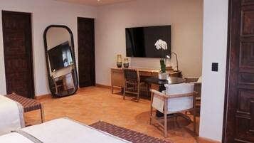 A hotel room with a bed, a desk, a chair, a television, and a large mirror.
