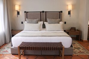 Un lit double avec une tête de lit, deux tables de chevet, un banc et un tapis.