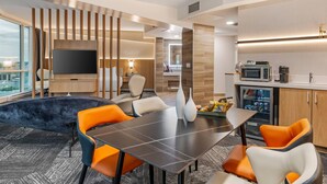 Una habitación de hotel moderna con comedor, televisión de pantalla plana, cocina y vista a la ciudad.