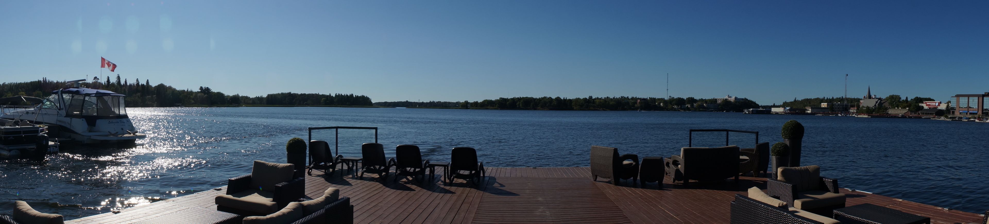 A wooden deck with outdoor seating and a view of a calm body of water.