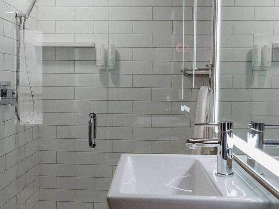 A modern bathroom with a walk-in shower, a large sink, and a mirror.