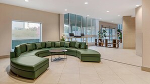Un vestíbulo amplio con un sofá seccional verde, una mesa redonda de centro y un gran ventanal con vistas al exterior.