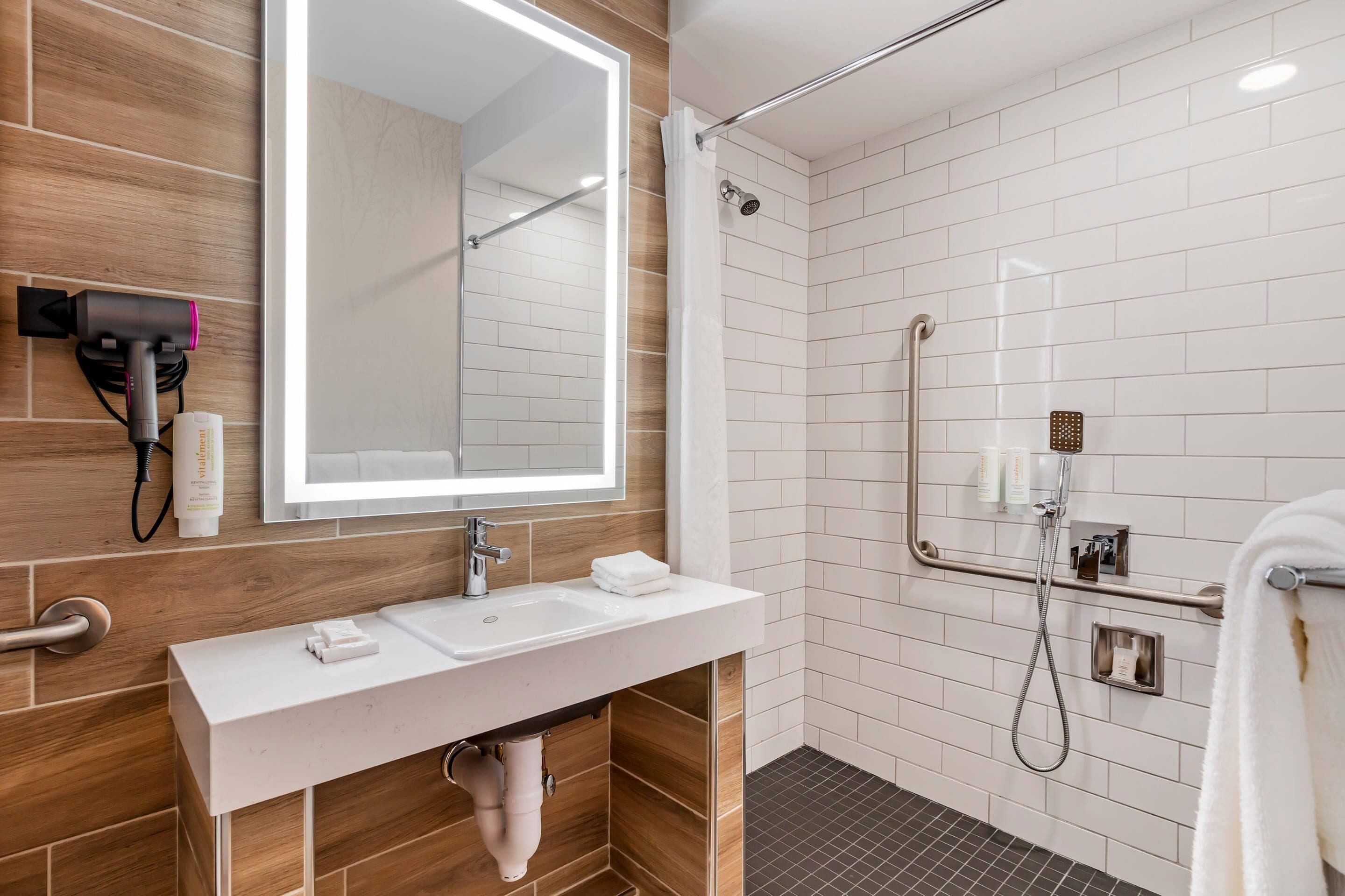 A modern bathroom with a white sink, mirror, and shower area.