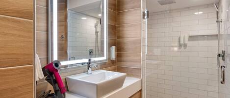 A modern bathroom with a large mirror, a sink, and a shower area.
