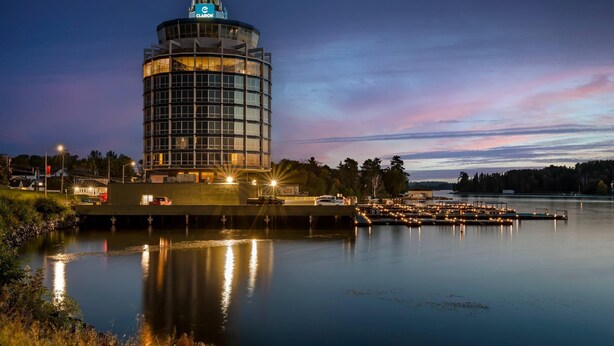 Un hotel moderno con una torre cilíndrica, vistas al agua y zona de embarcadero.