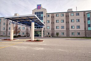 A hotel with a covered entrance, multiple windows, and a parking lot. - Motel 6 London, ON - Ontario (London)