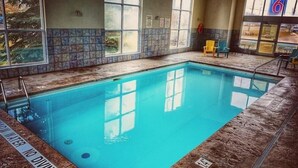 An indoor swimming pool with clear water, tiled walls, and windows. - Motel 6 London, ON - Ontario (London)