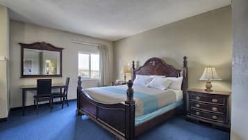 A bedroom with a large bed, a desk, a chair, a dresser, and a mirror.