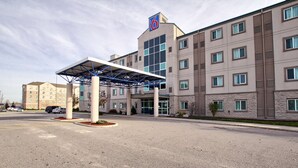 A hotel with a covered entrance, a large parking lot, and a multi-story building with a '6' logo. - Motel 6 London, ON - Ontario (London)