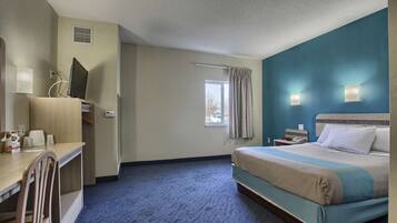 A hotel room with a bed, a desk, a chair, a window, and a nightstand.