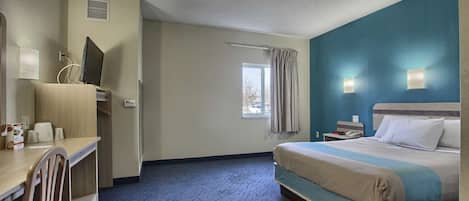 A hotel room with a bed, a desk, a chair, a window, and a nightstand.