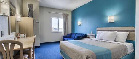 Hotelkamer met een bed, een bureau, een stoel, een raam met gordijnen en een wandlamp.