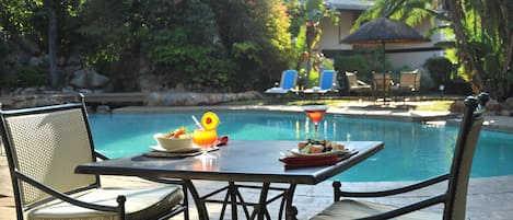 Una piscina al aire libre, sombrillas, sillones reclinables de piscina