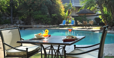 Una piscina al aire libre, sombrillas, sillones reclinables de piscina