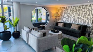 Ein modernes Wohnzimmer mit einem grauen Sofa, einem runden Couchtisch und Topfpflanzen.