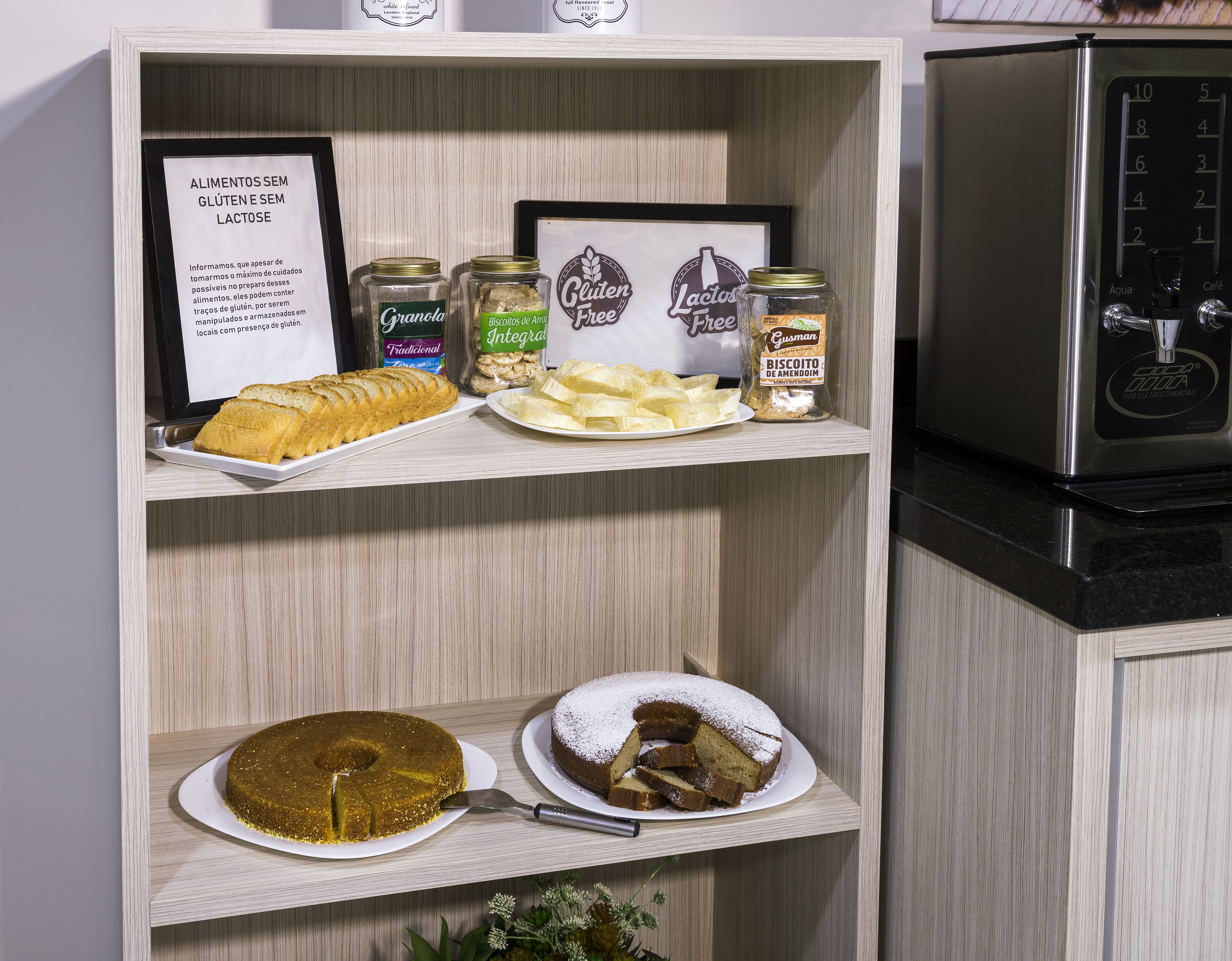 Una encimera de cocina con productos sin gluten ni lactosa, un pastel y una cafetera.