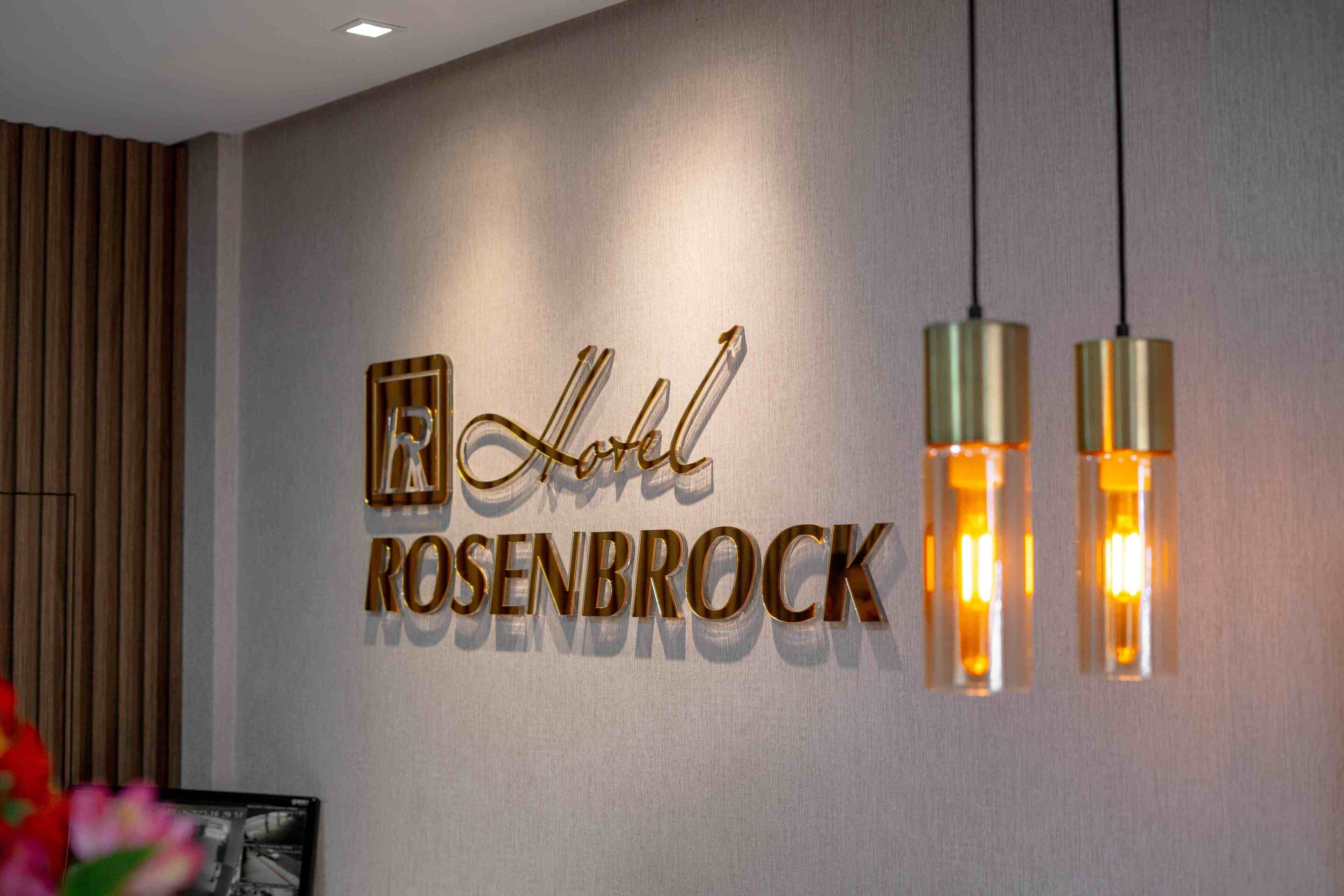A hotel sign with the name 'Hotel Rosenbrock' and two hanging pendant lights.