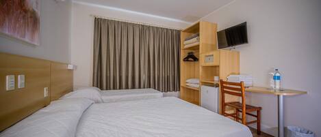 Una habitación de hotel con dos camas, un escritorio, una silla, un televisor y un armario.