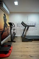 Un gimnasio con cintas de correr, una bicicleta estática y una plataforma roja para ejercicios.