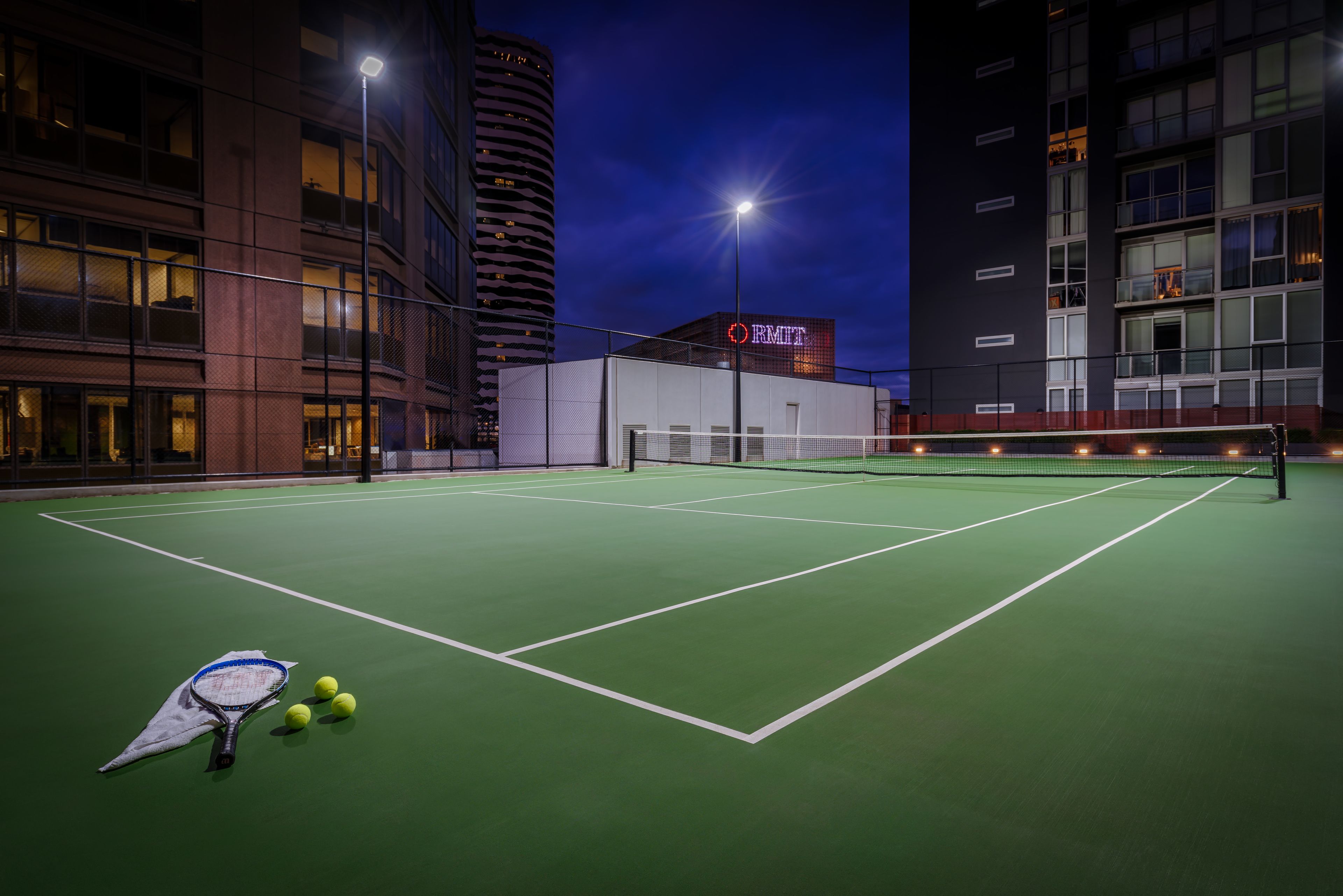 An indoor tennis court with a net, a tennis racket, and balls.